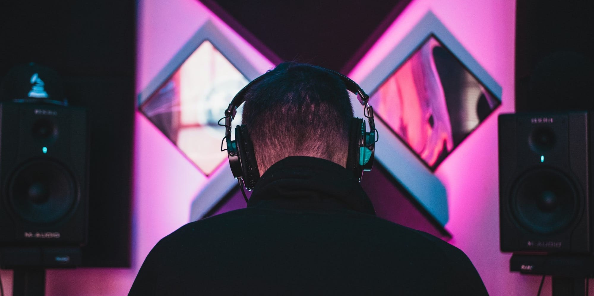 man wearing black headphones near two PA speakers